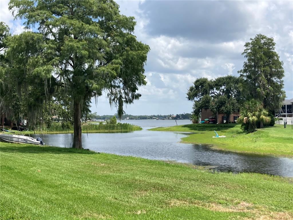 A white picket fence overlooks a pond with a small boat and apartment buildings beyond — 13709 JUNIPER BLOSSOM DRIVE UNIT 0, TAMPA, FL