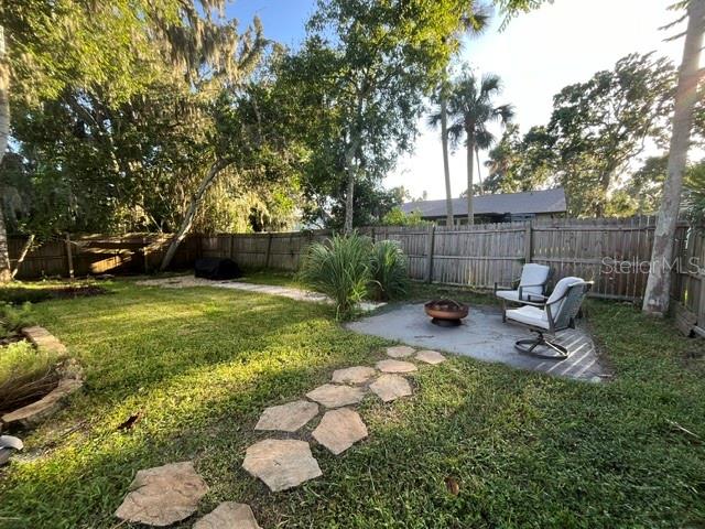 A backyard features a stone path, a fire pit, and two chairs on a concrete patio — 3444 GELDING COURT, PORT ORANGE, FL