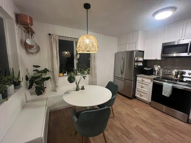 A kitchen features white cabinets, stainless steel appliances, a round dining table, and wood-look flooring — 3444 GELDING COURT, PORT ORANGE, FL