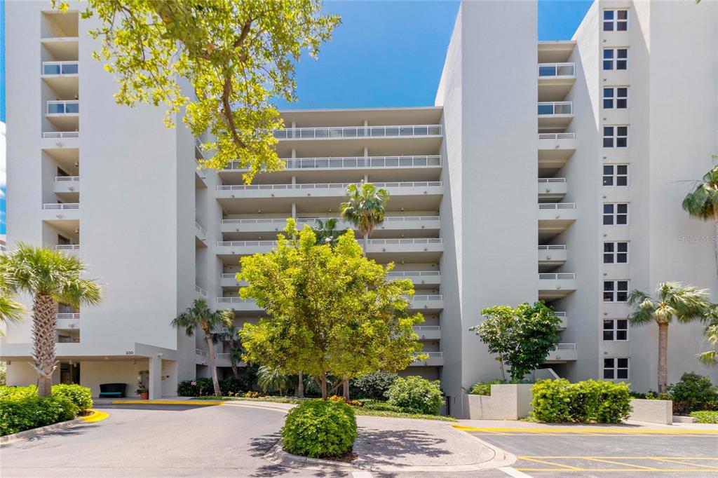 A multi-story apartment building with balconies and a paved driveway entrance — 230 SANDS POINT ROAD UNIT 3205, LONGBOAT KEY, FL
