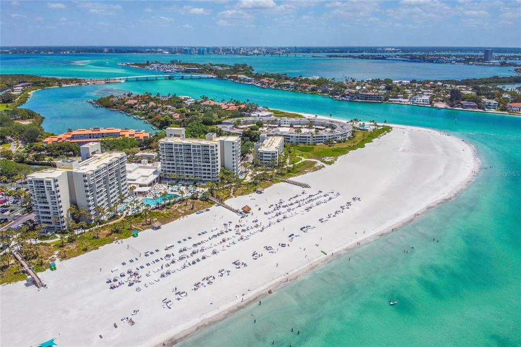 An aerial view shows a sandy beach, turquoise water, and several large residential buildings — 230 SANDS POINT ROAD UNIT 3205, LONGBOAT KEY, FL