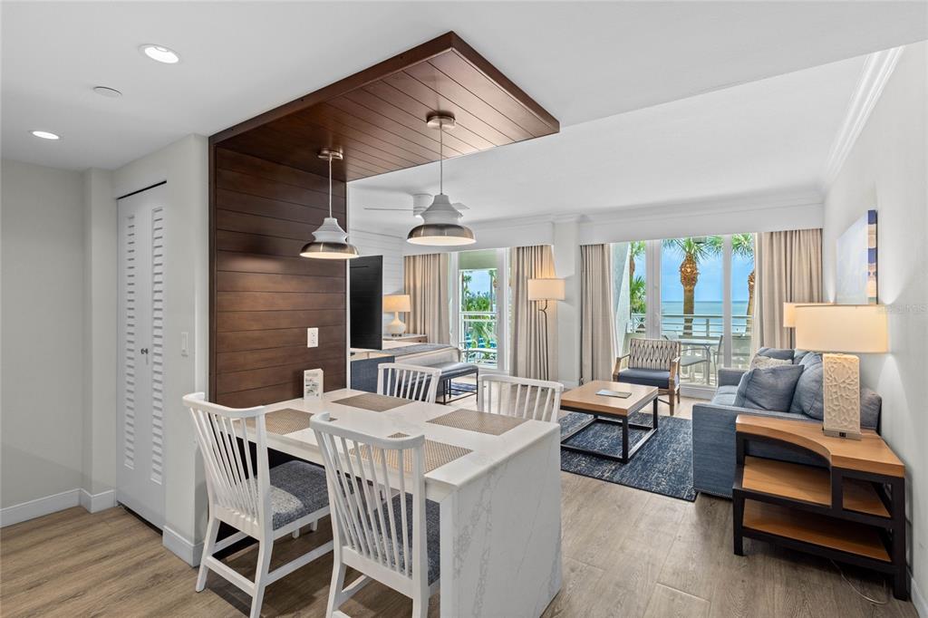 A dining area with a wood-paneled ceiling feature opens into a living room with ocean views — 230 SANDS POINT ROAD UNIT 3205, LONGBOAT KEY, FL
