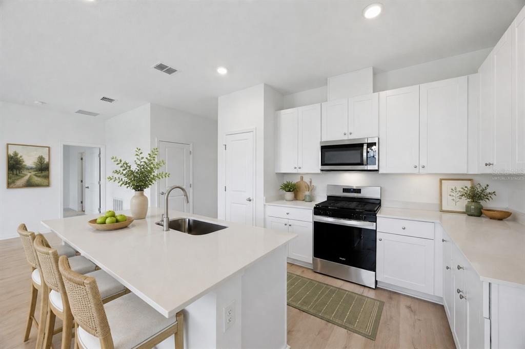 A bathroom features a white vanity, a toilet, and a bathtub with a tiled surround — 6205 SANDERS GROVE CIRCLE, OKAHUMPKA, FL
