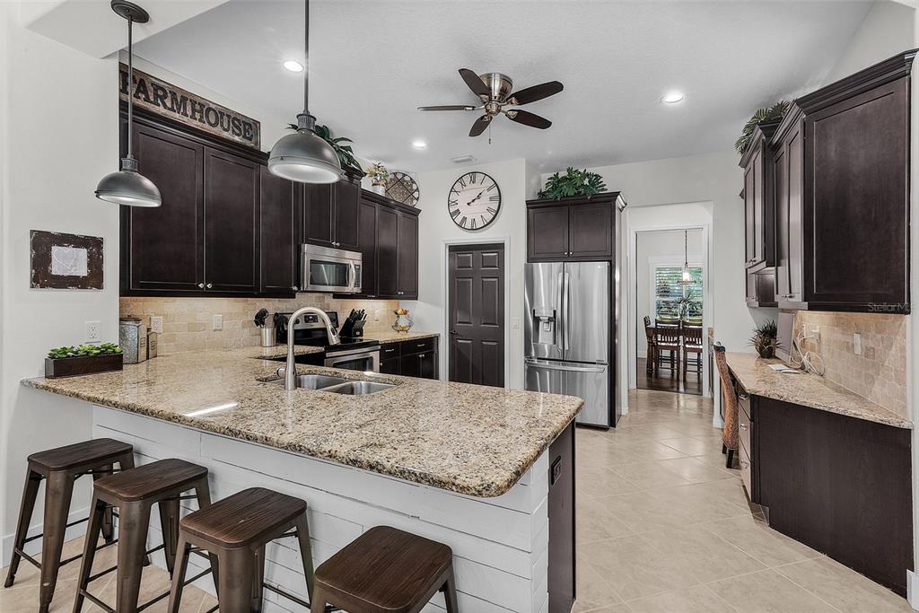 A kitchen features dark wood cabinets, granite countertops, a breakfast bar, and stainless steel appliances — 3015 160TH TERRACE E, PARRISH, FL