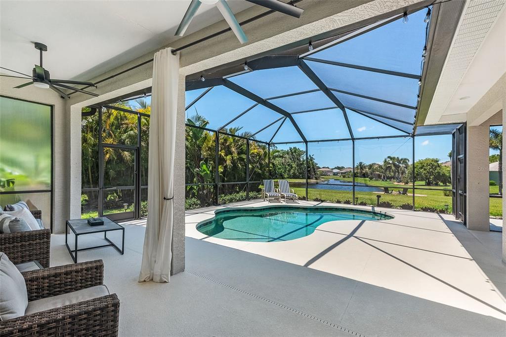 A covered patio with a pool cage overlooks a swimming pool and a grassy backyard — 3015 160TH TERRACE E, PARRISH, FL