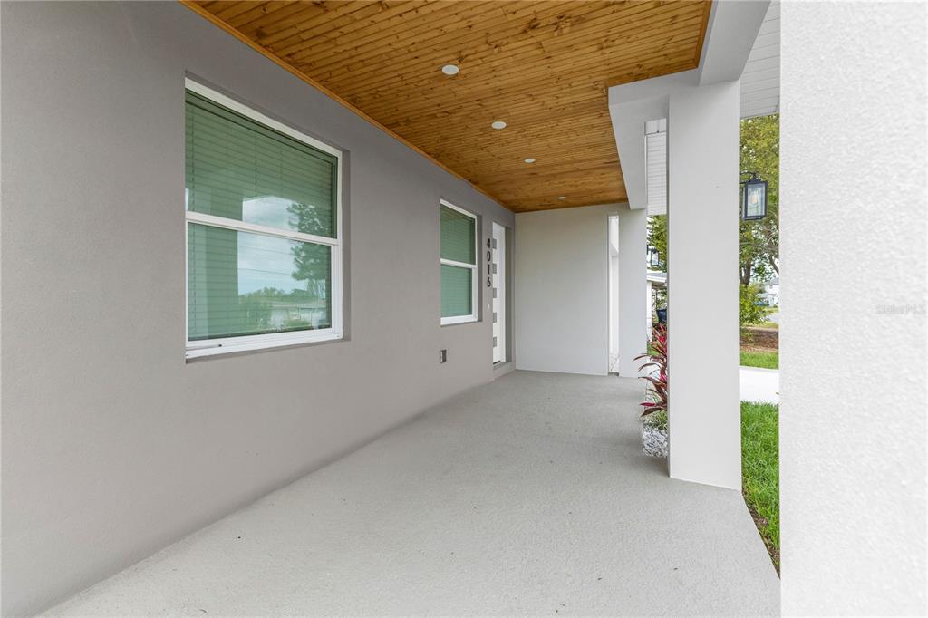 A covered porch features a wood-paneled ceiling, gray walls, and a concrete floor — 4016 BADEN DRIVE, HOLIDAY, FL