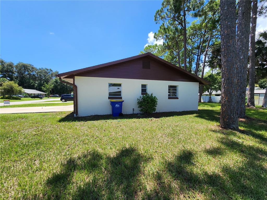 The exterior side view of a white house with a brown gable roof and windows — 2304 INDIA PALM DRIVE, EDGEWATER, FL