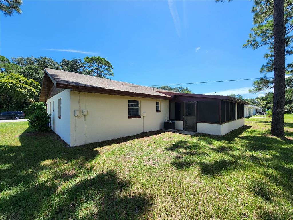 The exterior of a single-story house features a screened-in porch and a grassy backyard — 2304 INDIA PALM DRIVE, EDGEWATER, FL