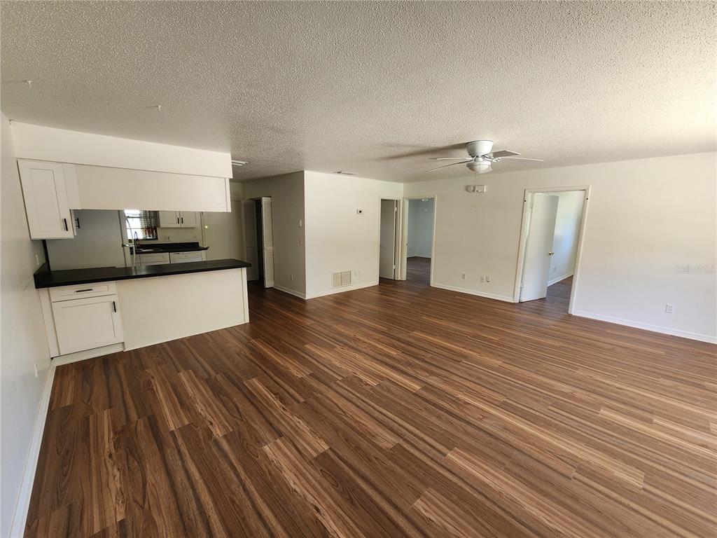 An open-concept living area features white kitchen cabinetry, a dark countertop, and wood-look flooring — 2304 INDIA PALM DRIVE, EDGEWATER, FL