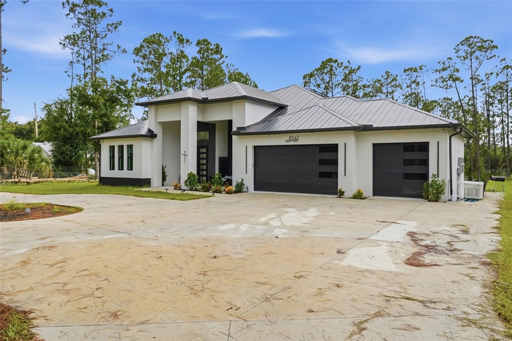 A modern white house with a metal roof and a large concrete driveway — 6547 BEEDLA STREET, NORTH PORT, FL