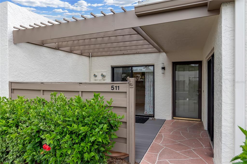 A patio entrance features a wooden pergola, a privacy fence, and a stone-tiled walkway — 511 LAKESIDE DRIVE UNIT 511, BRADENTON, FL