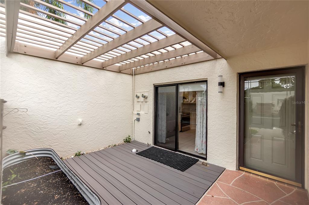 A patio features a wooden pergola, a gray deck, and a sliding glass door — 511 LAKESIDE DRIVE UNIT 511, BRADENTON, FL