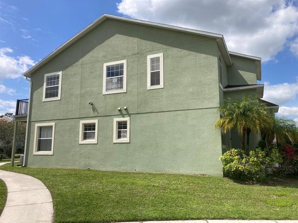A two-story green stucco building with multiple windows and a palm tree on the side — 4324 PARADISE COVE COURT, KISSIMMEE, FL