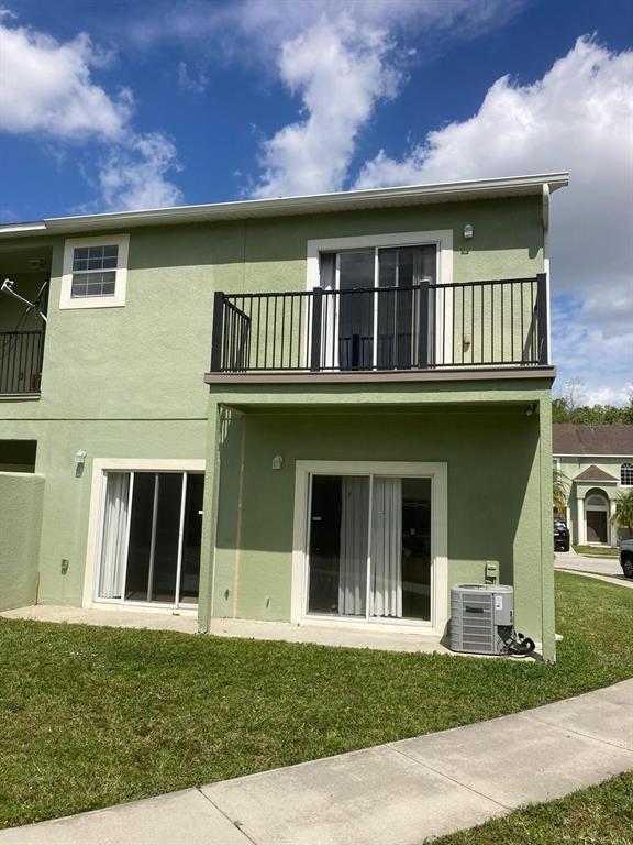 The exterior of a two-story green townhouse features a second-floor balcony and sliding glass doors — 4324 PARADISE COVE COURT, KISSIMMEE, FL