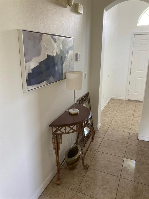 A hallway features a semi-circular console table, a lamp, wall art, and tiled flooring — 4324 PARADISE COVE COURT, KISSIMMEE, FL