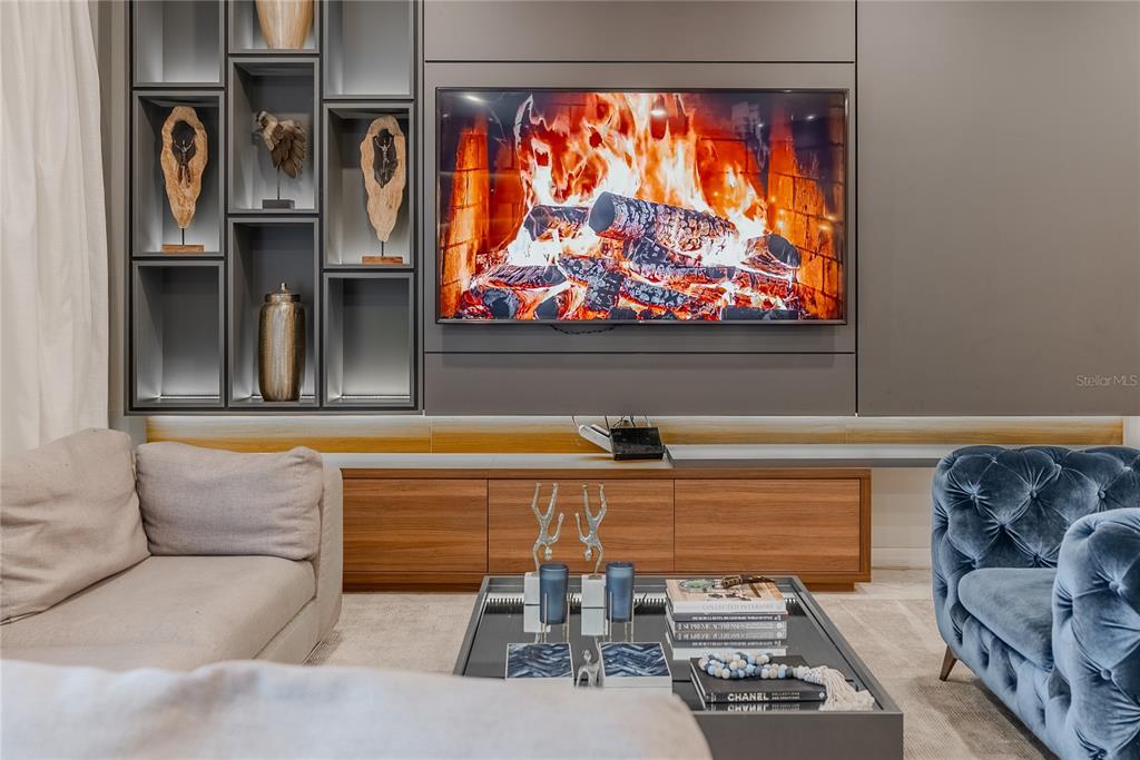 A living room features a wall-mounted television, built-in shelving, a wooden console, and plush seating — 2126 LELANI CIRCLE, DAVENPORT, FL