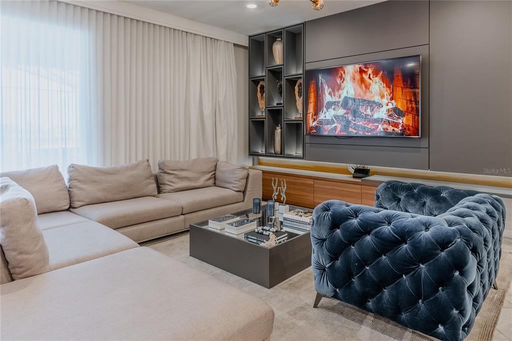 A living room features a large sectional sofa, a tufted blue armchair, and a fireplace television — 2126 LELANI CIRCLE, DAVENPORT, FL