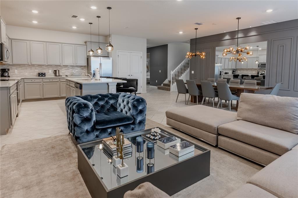 An open-concept living room features a blue tufted chair, mirrored coffee table, and dining area — 2126 LELANI CIRCLE, DAVENPORT, FL