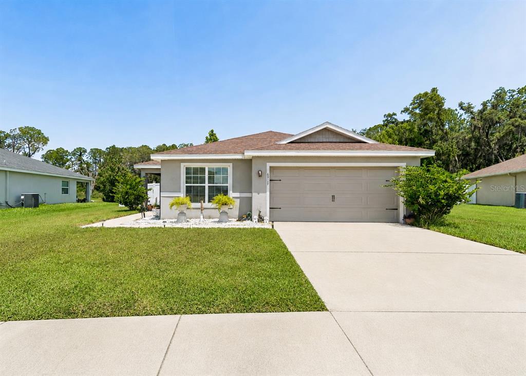 A single-story house with a beige exterior, a two-car garage, and a concrete driveway — 6917 GIDEON CIRCLE, ZEPHYRHILLS, FL