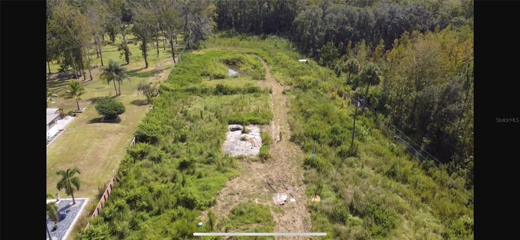 An aerial view of a grassy, overgrown lot with a concrete foundation and small pond — 805 BARON ROAD, ORLANDO, FL
