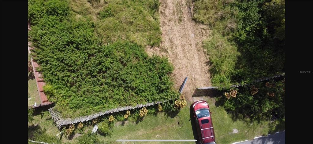 An aerial view shows a red vehicle parked in front of a fenced, overgrown vacant lot — 805 BARON ROAD, ORLANDO, FL