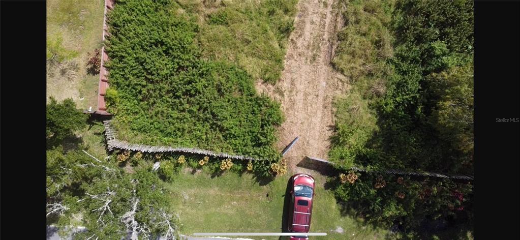 An aerial view shows a red car parked in front of a fenced, overgrown vacant lot — 805 BARON ROAD, ORLANDO, FL