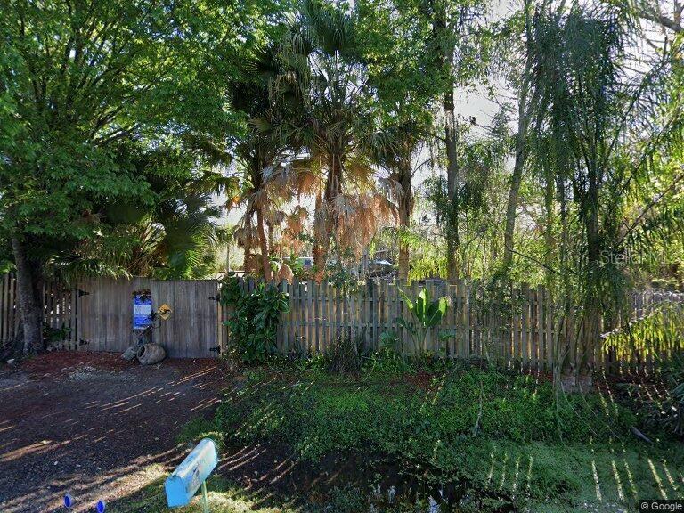 A wooden fence encloses a lush, tree-filled yard with a blue mailbox in the foreground — 805 BARON ROAD, ORLANDO, FL