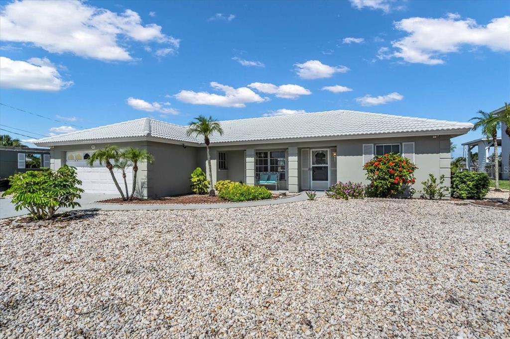 A single-story house with a white tile roof, gray exterior, and a gravel front yard — 3816 ROYAL PALM DRIVE, BRADENTON, FL