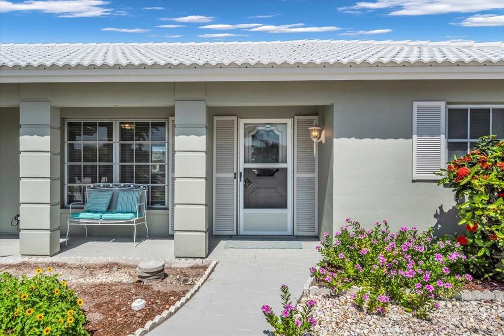 A light-colored house exterior features a white-tiled roof, a front porch, and a screen door — 3816 ROYAL PALM DRIVE, BRADENTON, FL