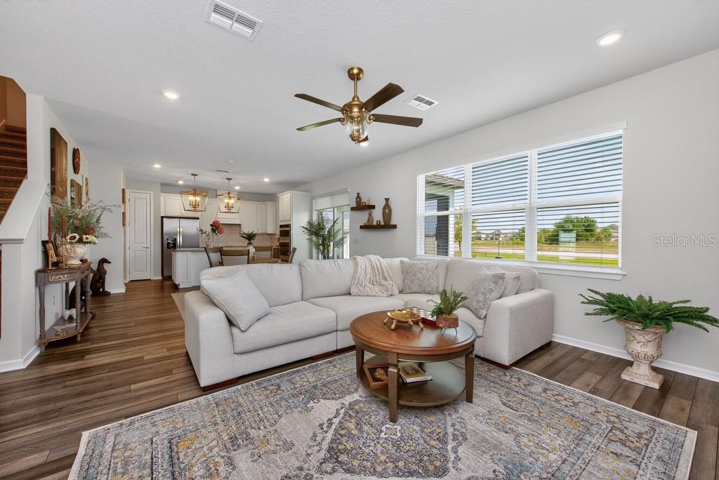 A living room with a sectional sofa, round coffee table, and open kitchen in background — 12908 BROOKSIDE MOSS DRIVE, RIVERVIEW, FL