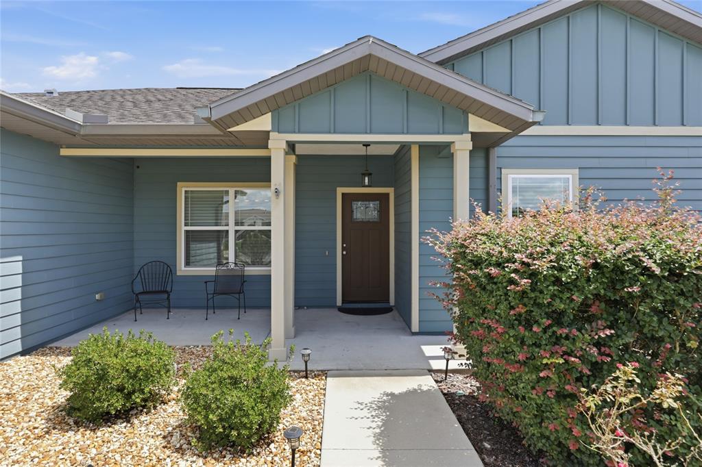 The exterior of a blue house features a covered front porch and a brown door — 22971 NW 6TH LANE, NEWBERRY, FL