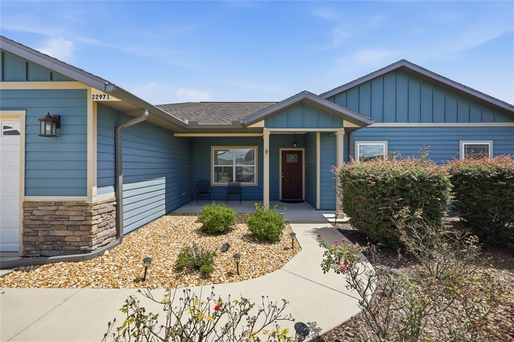 The exterior of a blue house features a stone base, a walkway, and landscaping — 22971 NW 6TH LANE, NEWBERRY, FL