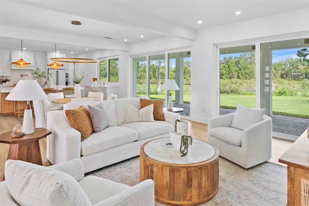 A bright living room features a white sofa, two armchairs, and sliding glass doors to outdoors — 2202 NEWBERGER ROAD, LUTZ, FL
