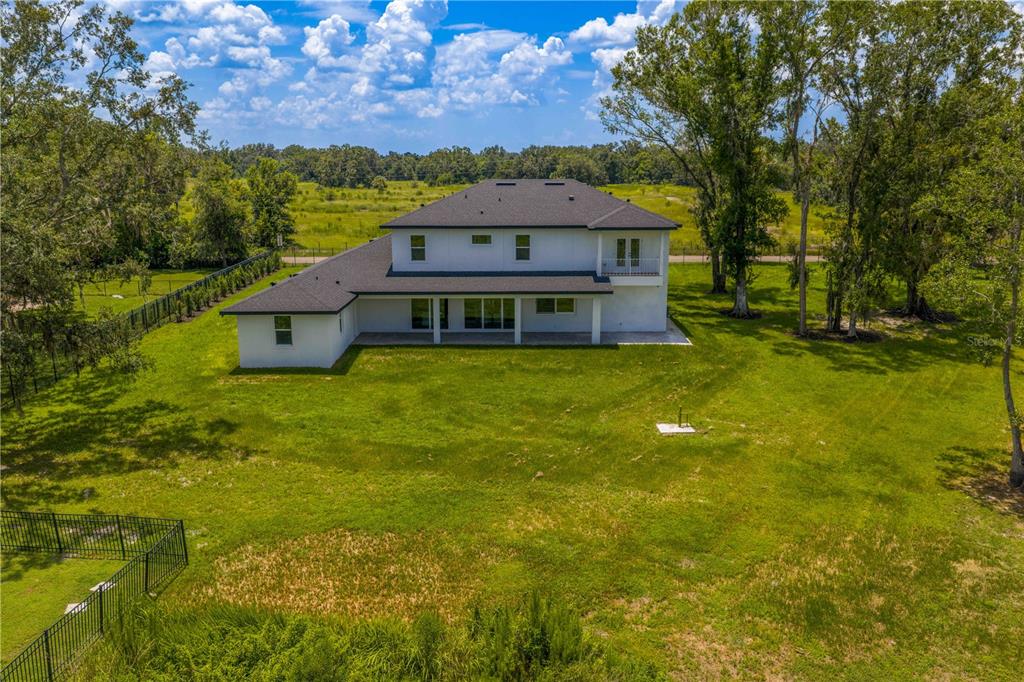 An aerial view of the back of a two-story white house with a dark roof — 2202 NEWBERGER ROAD, LUTZ, FL