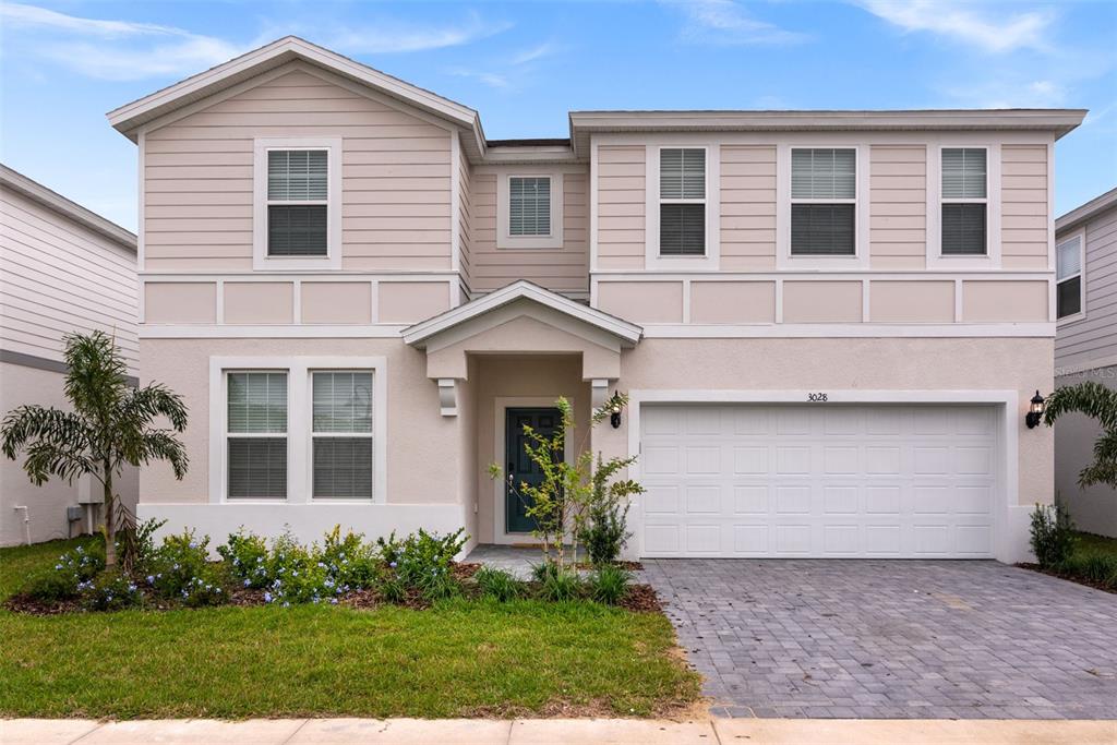 A two-story suburban house features a light-colored exterior, a two-car garage, and a front yard — 3028 MAHALO DRIVE, DAVENPORT, FL