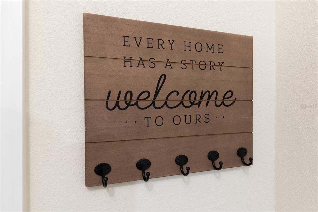 A wooden wall-mounted sign with hooks hangs on a plain interior wall — 3028 MAHALO DRIVE, DAVENPORT, FL