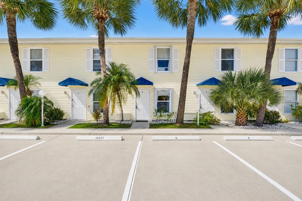 A row of yellow townhouses with palm trees and assigned parking spaces in front — 26310 RAMPART BOULEVARD UNIT D504, PUNTA GORDA, FL