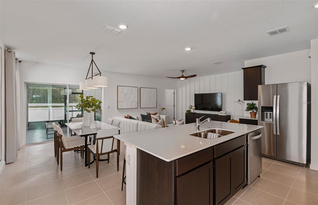 An open-concept kitchen and living area featuring dark wood cabinets, a quartz island, and tile flooring — 5266 CURRANT STREET, LAKELAND, FL