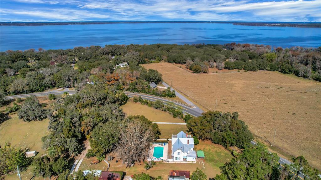An aerial view shows a house with a pool situated on a large, grassy lot — 9210 COUNTY ROAD 48, YALAHA, FL