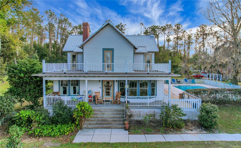 A two-story house with a metal roof, a wrap-around porch, and an outdoor swimming pool — 9210 COUNTY ROAD 48, YALAHA, FL