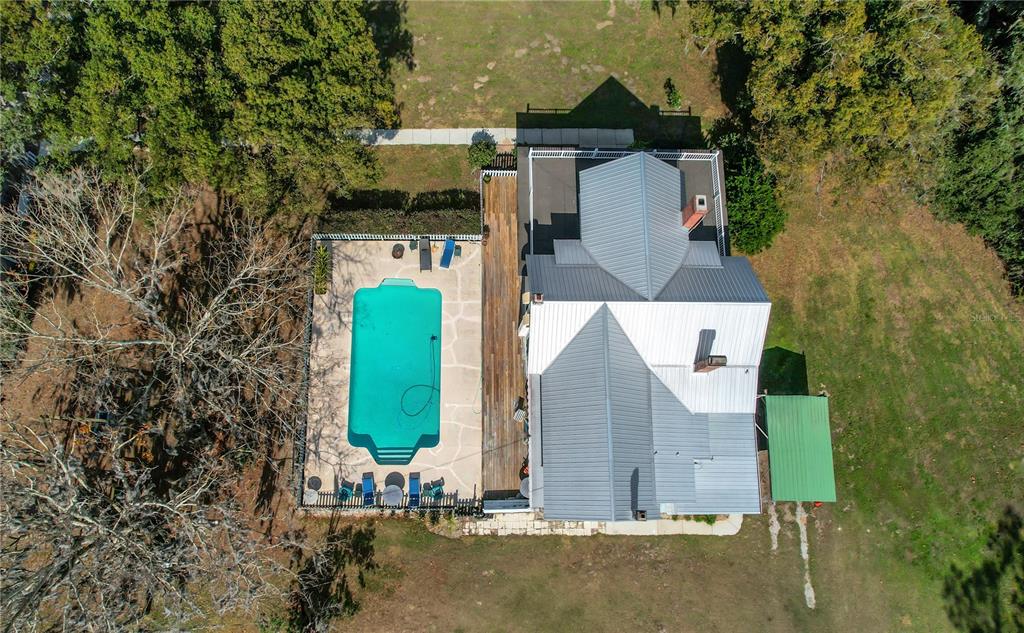 An aerial view shows a house with a metal roof, a swimming pool, and wooden decking — 9210 COUNTY ROAD 48, YALAHA, FL