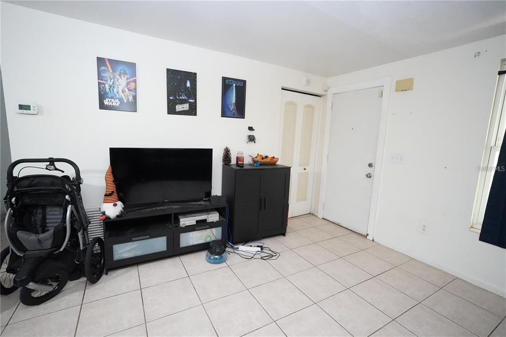 A living room with white walls, tiled floors, a television console, and a baby stroller — 14611 SW 37TH COURT, OCALA, FL