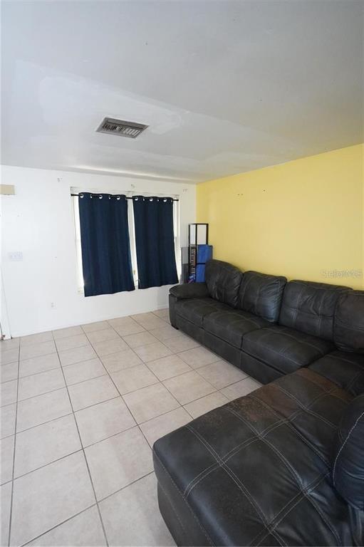 A living room features a dark leather sectional sofa, tiled floors, and a yellow wall — 14611 SW 37TH COURT, OCALA, FL