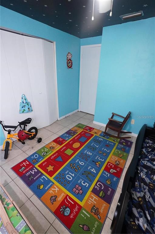 A child's bedroom features light blue walls, a star-patterned ceiling, tile flooring, and an educational rug — 14611 SW 37TH COURT, OCALA, FL