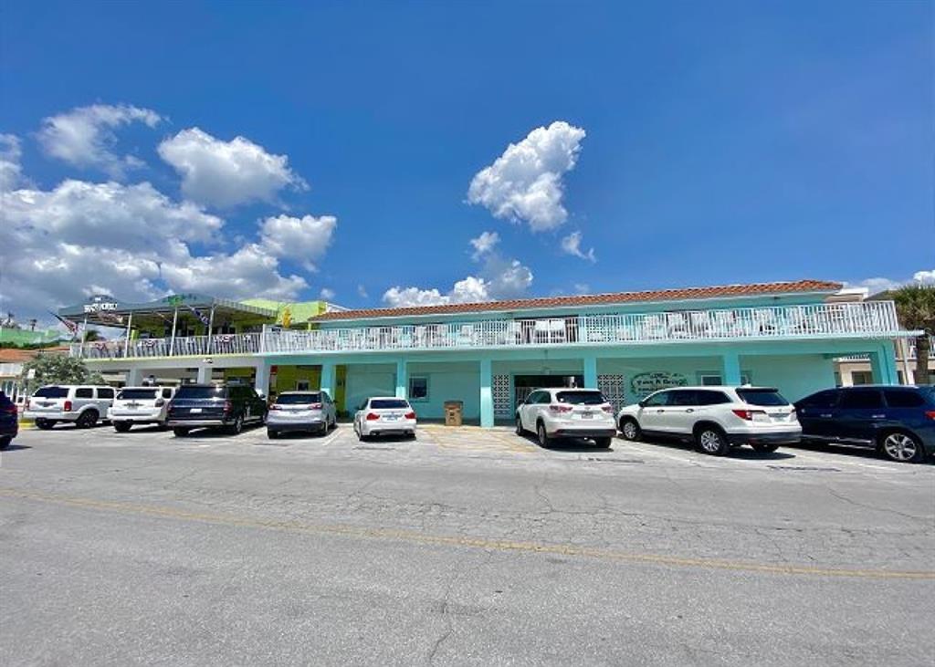 A light blue two-story commercial building with a parking lot in front — 709 GULF WAY UNIT 19, ST PETE BEACH, FL
