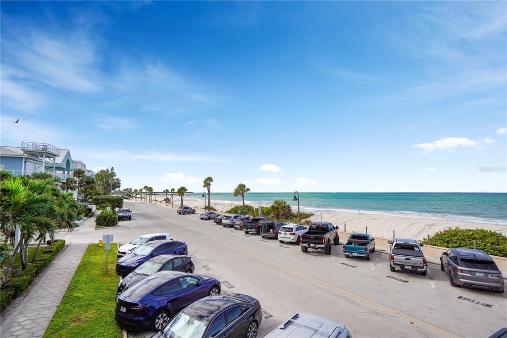 An elevated view of a beachside parking lot with cars parked along a coastal road — 709 GULF WAY UNIT 19, ST PETE BEACH, FL