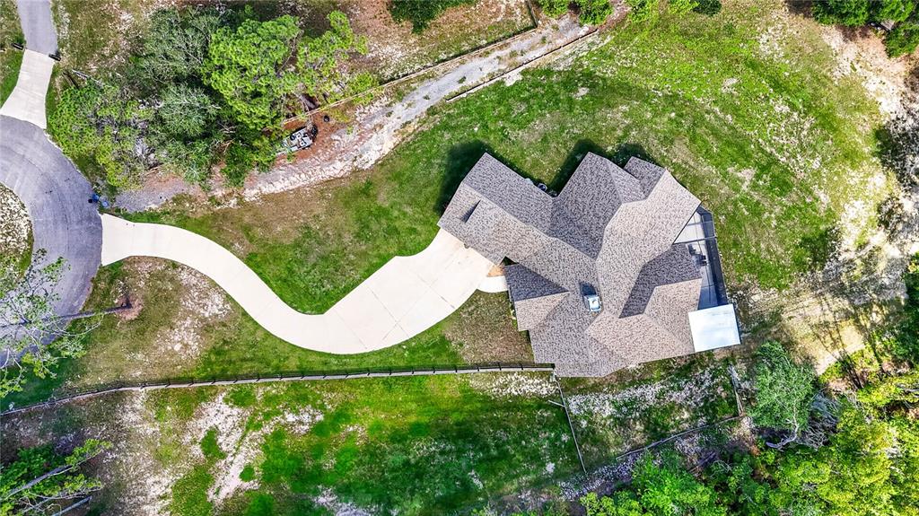 An aerial view shows a house with a complex roofline, driveway, and surrounding wooded yard — 17265 MEADOW BLUFF VIEW, DADE CITY, FL