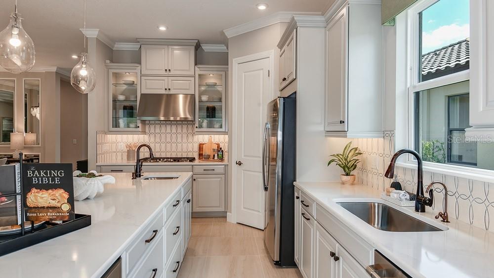A modern kitchen features white cabinetry, quartz countertops, stainless steel appliances, and a large island — 29668 IMPERATI BOULEVARD, WESLEY CHAPEL, FL