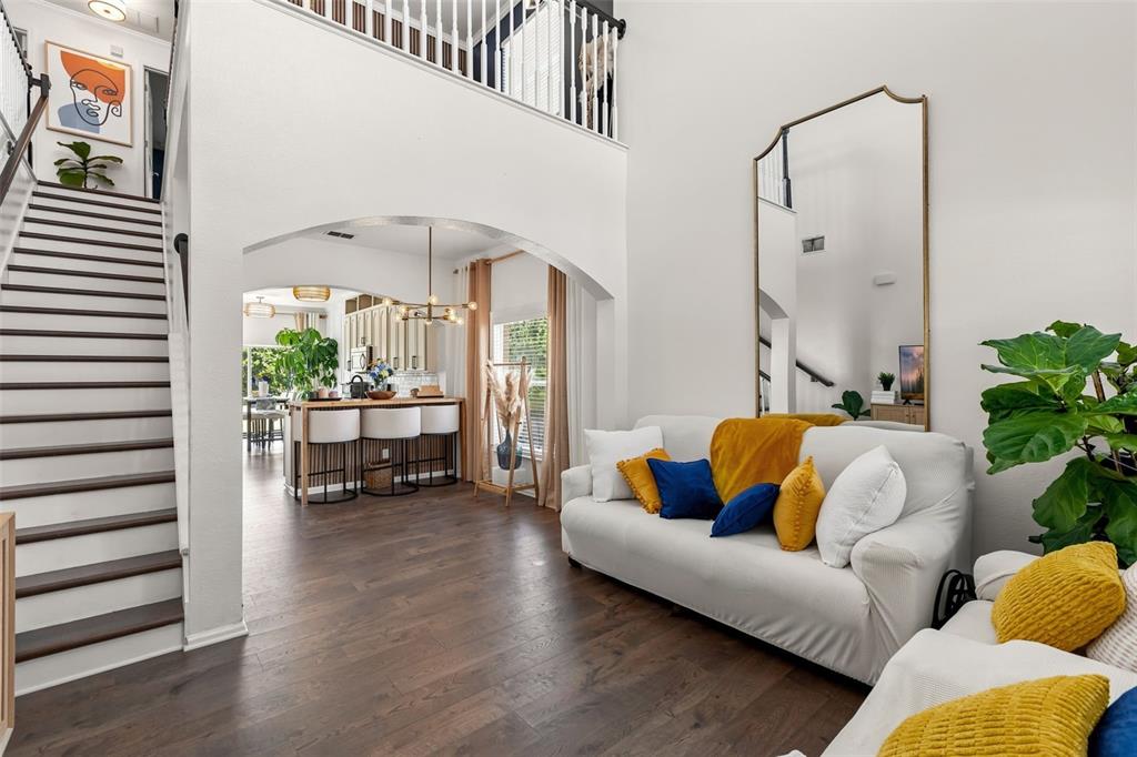 A living room with a white sofa, arched entryway, staircase, and view into the kitchen — 16424 CEDAR CREST DRIVE, ORLANDO, FL