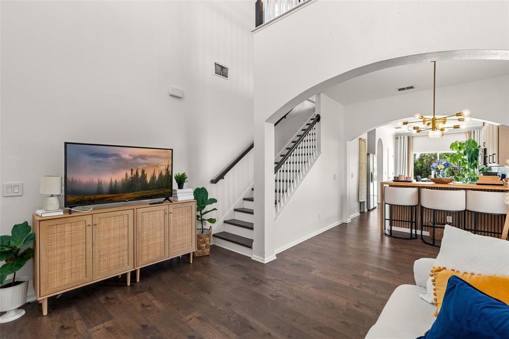 A living area with a television console, staircase, and an open kitchen with bar seating — 16424 CEDAR CREST DRIVE, ORLANDO, FL